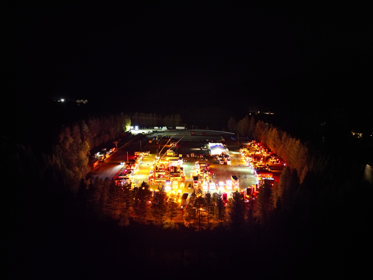 Oversiktsbilde på avstand av det opplyste festivalområdet omgitt av skog.