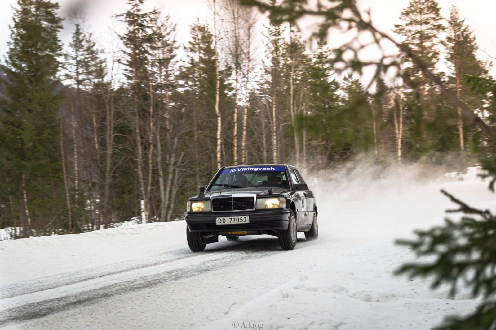 Svart Mercedes med snøsprut bak bilen.