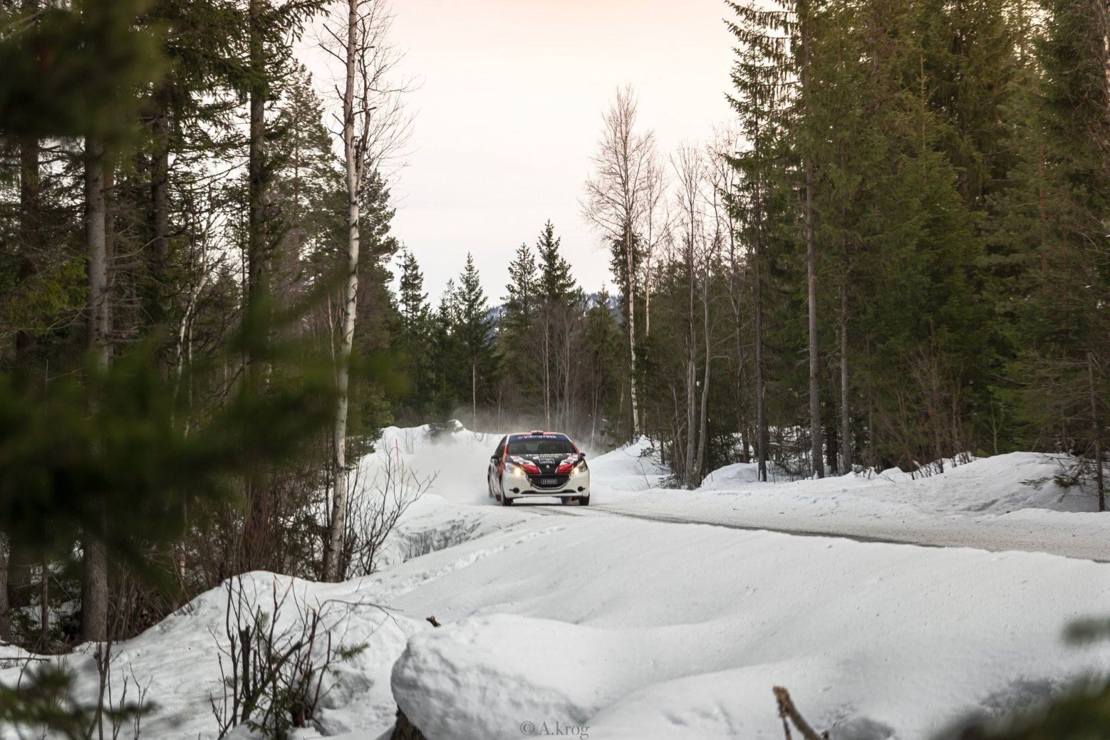 Rød og hvit rallybil på svingete snøvei.